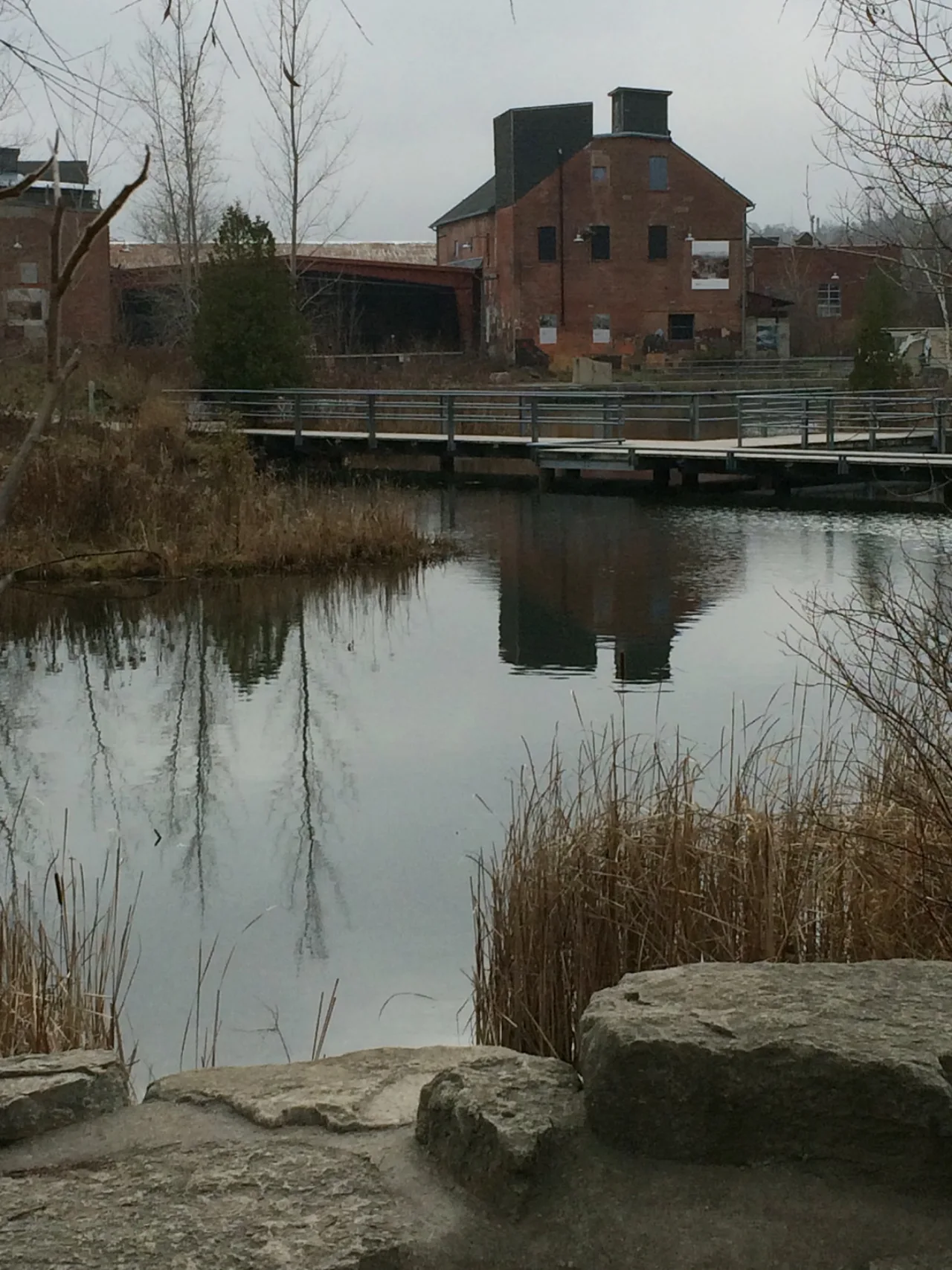 A former brick factory building and footbridge reflected in a pond at Evergreen Brick Works.
