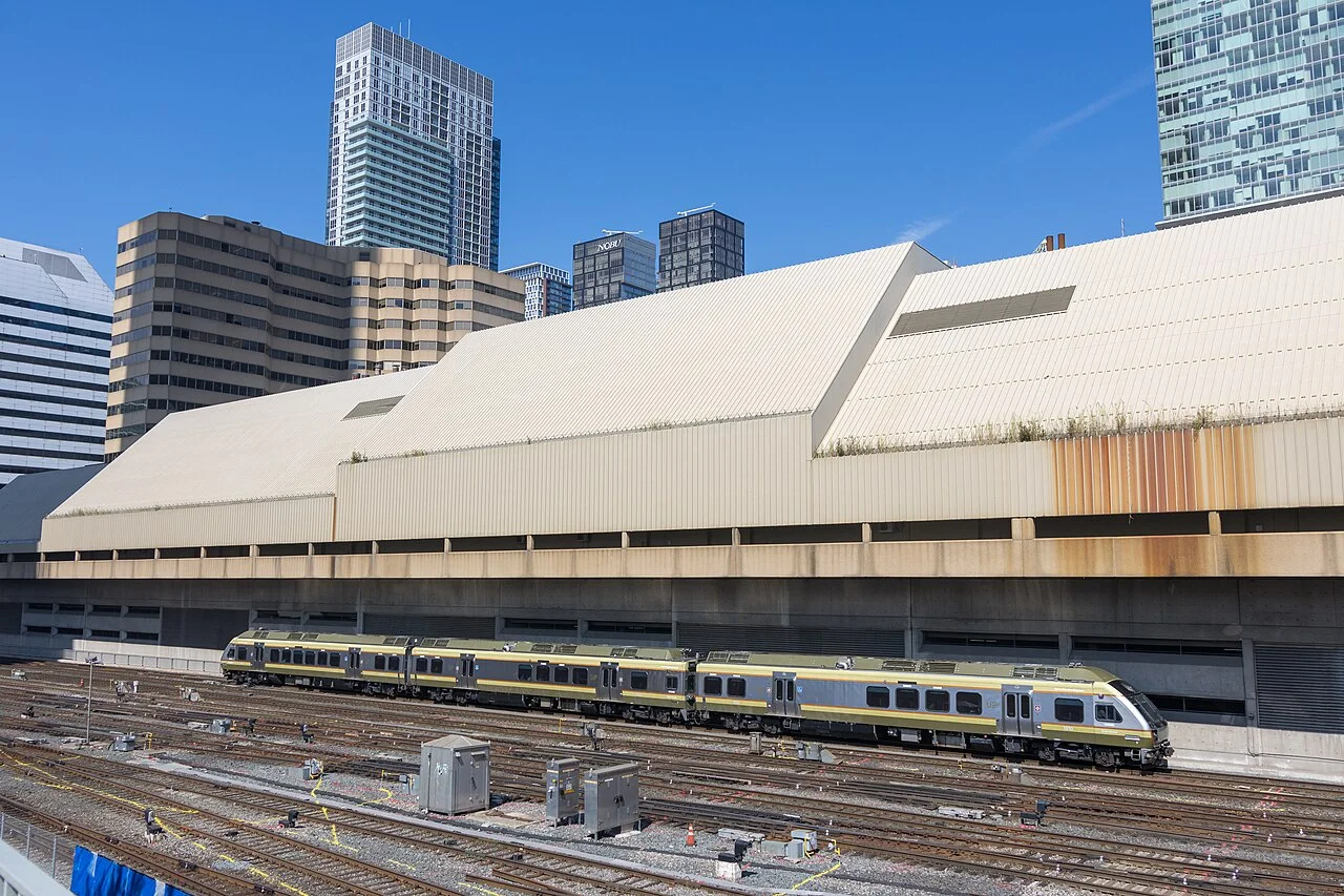 An UP Express train travelling beside the Metro Toronto Convention Centre on the approach to Union Station.