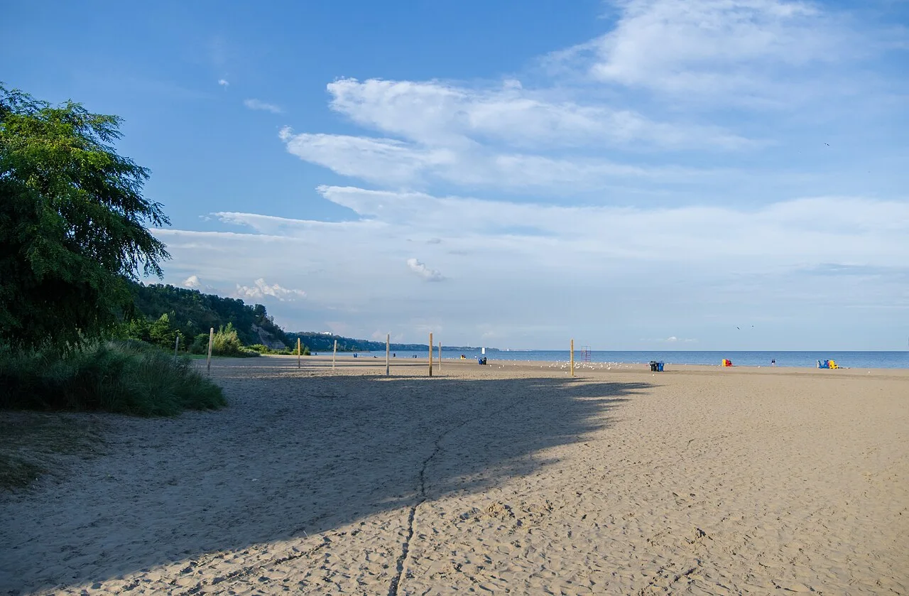 A broad sandy beach at Bluffer’s Park with the lake ahead and bluffs in the distance.