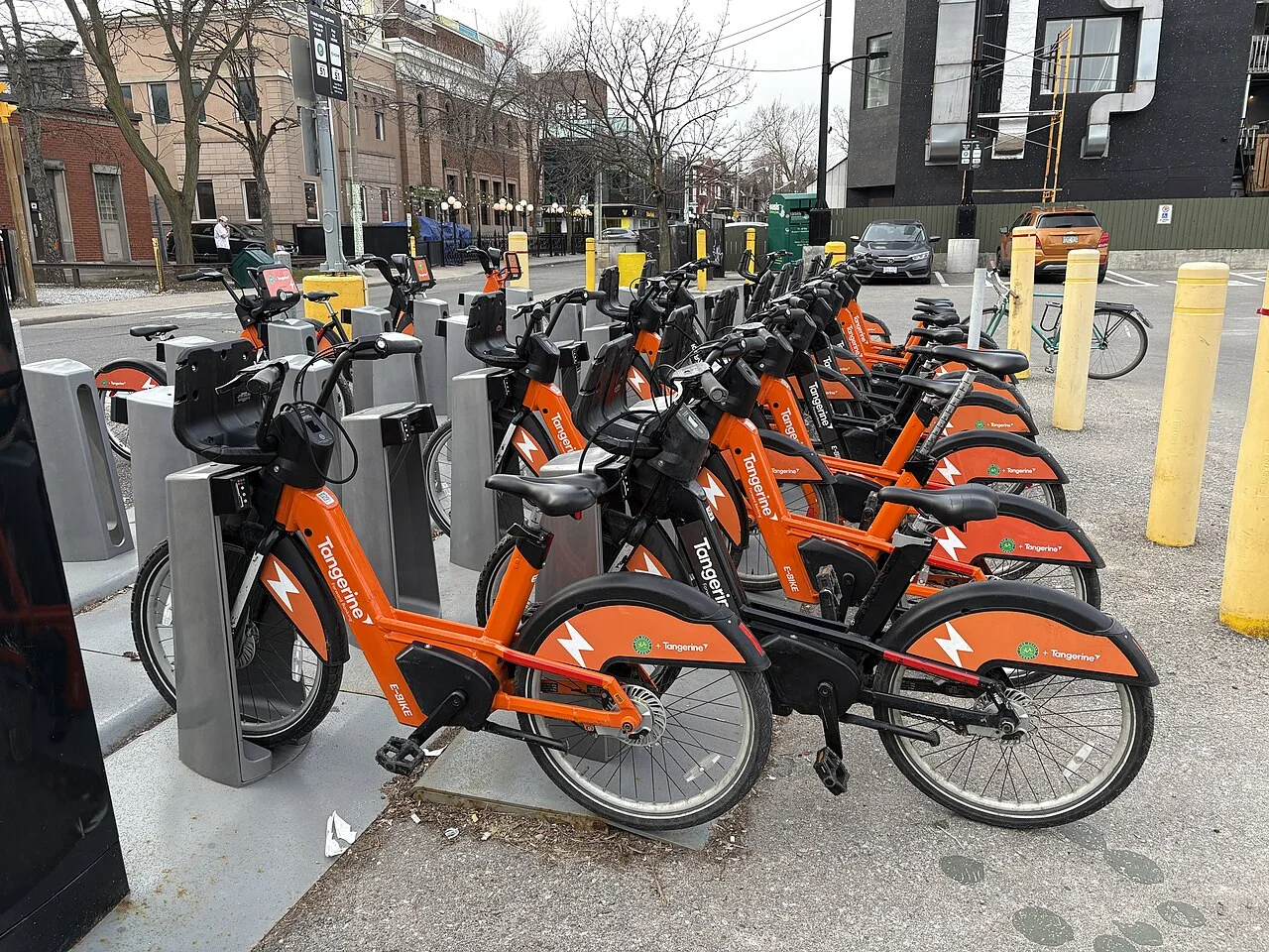 Orange Bike Share Toronto e-bikes lined up at an electric docking station