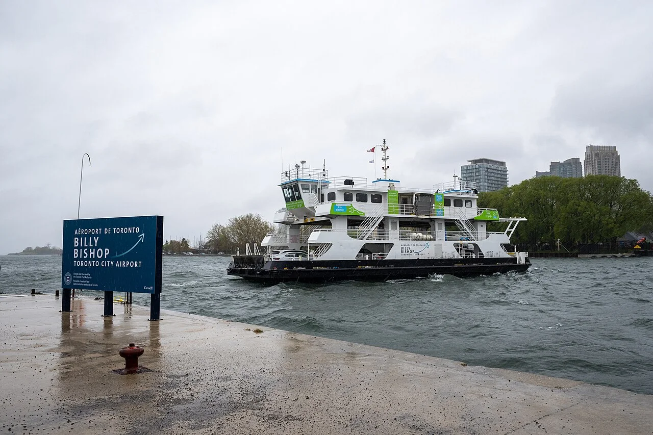 The Marilyn Bell electric ferry crossing beside the Billy Bishop Airport sign