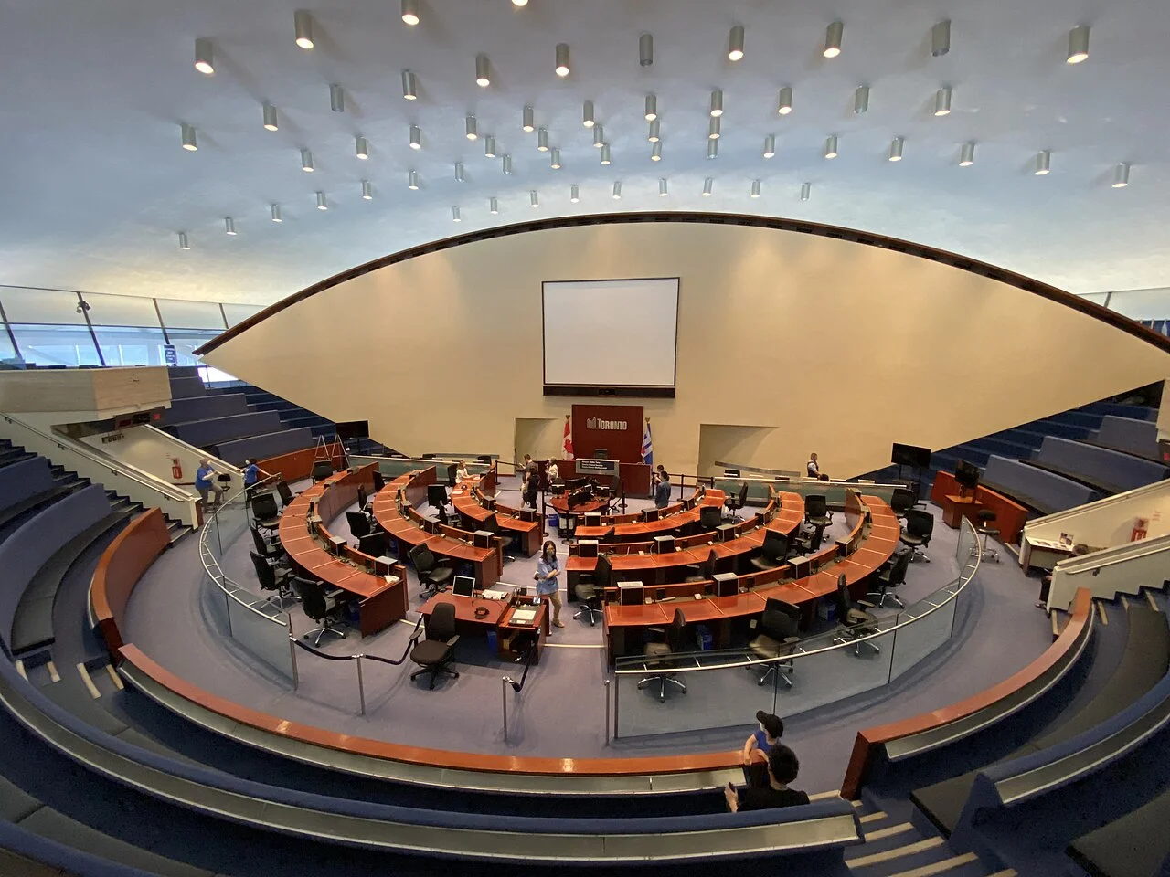 Curved rows of desks and public seating inside Toronto City Hall’s council chamber.