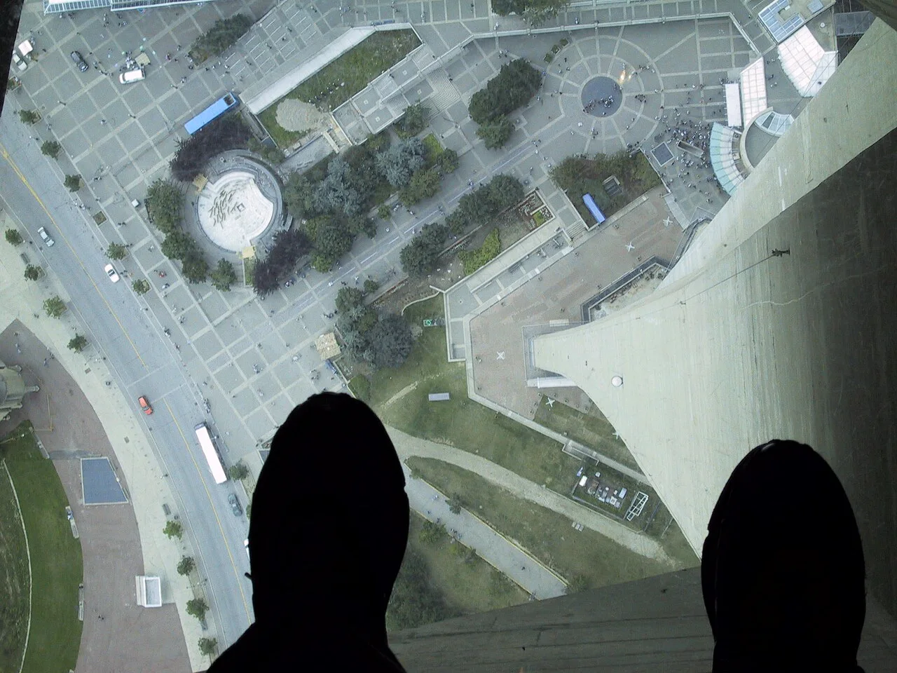 Feet on the CN Tower glass floor above the surrounding plaza.