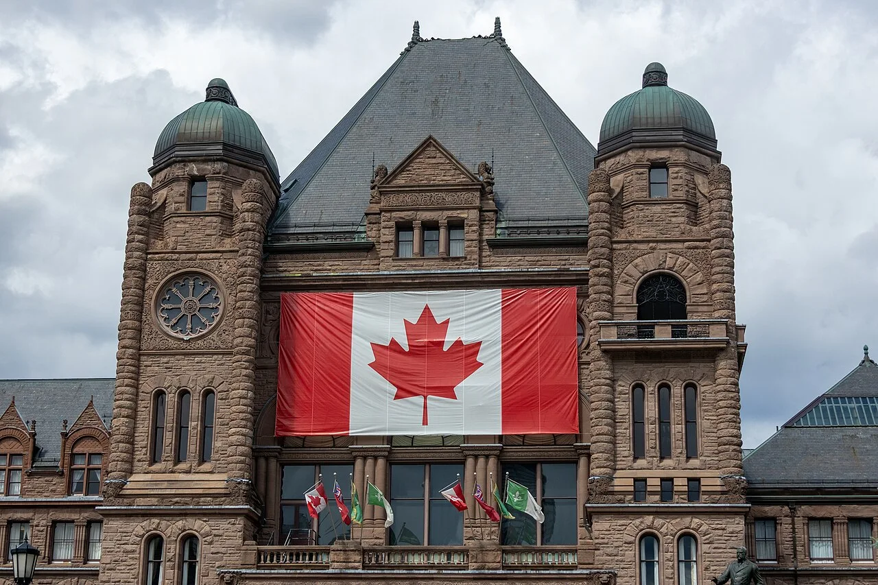 Ontario Legislative Building façade with a Canadian flag at Queen’s Park.