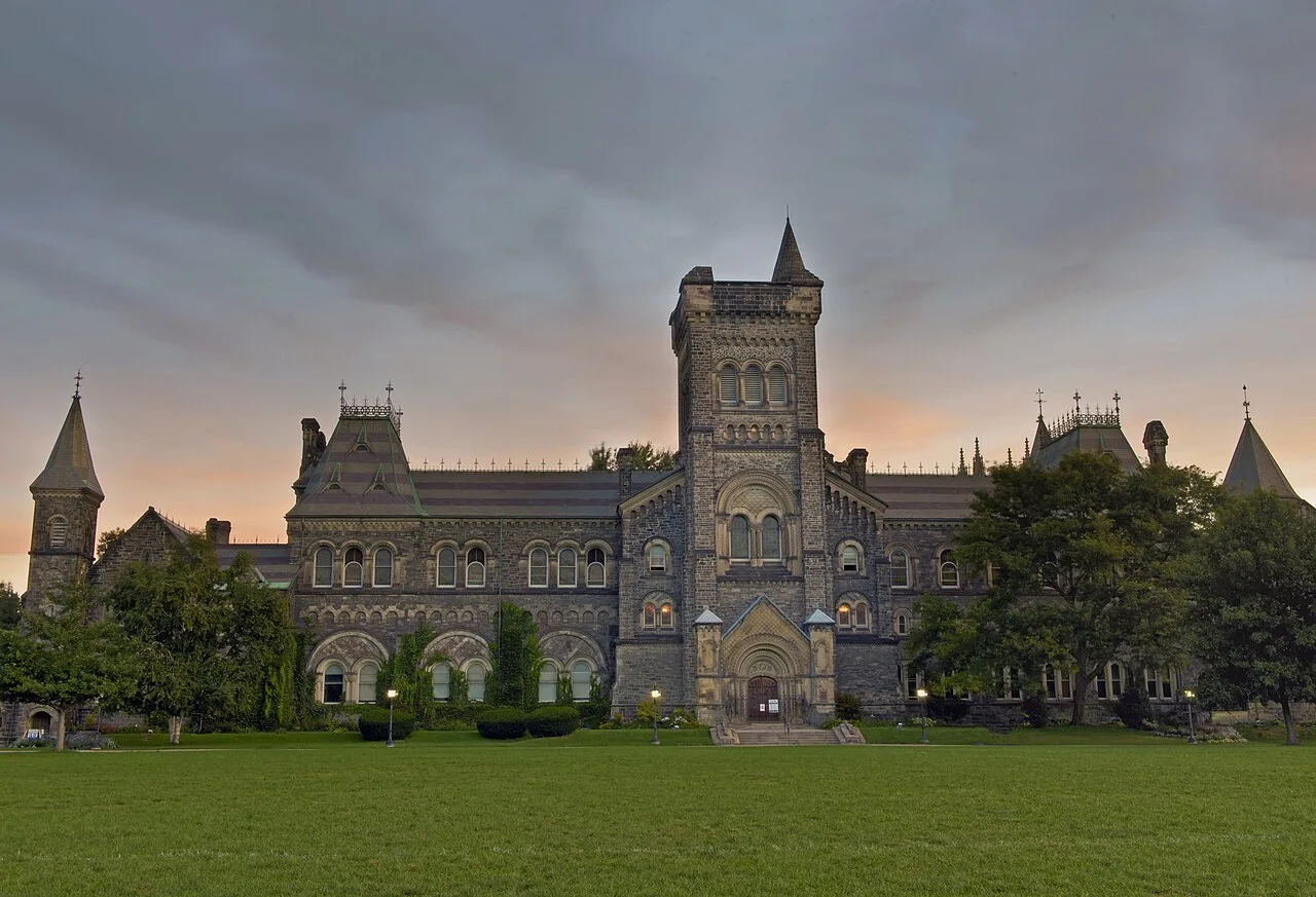 University College’s stone façade and central tower behind a lawn.