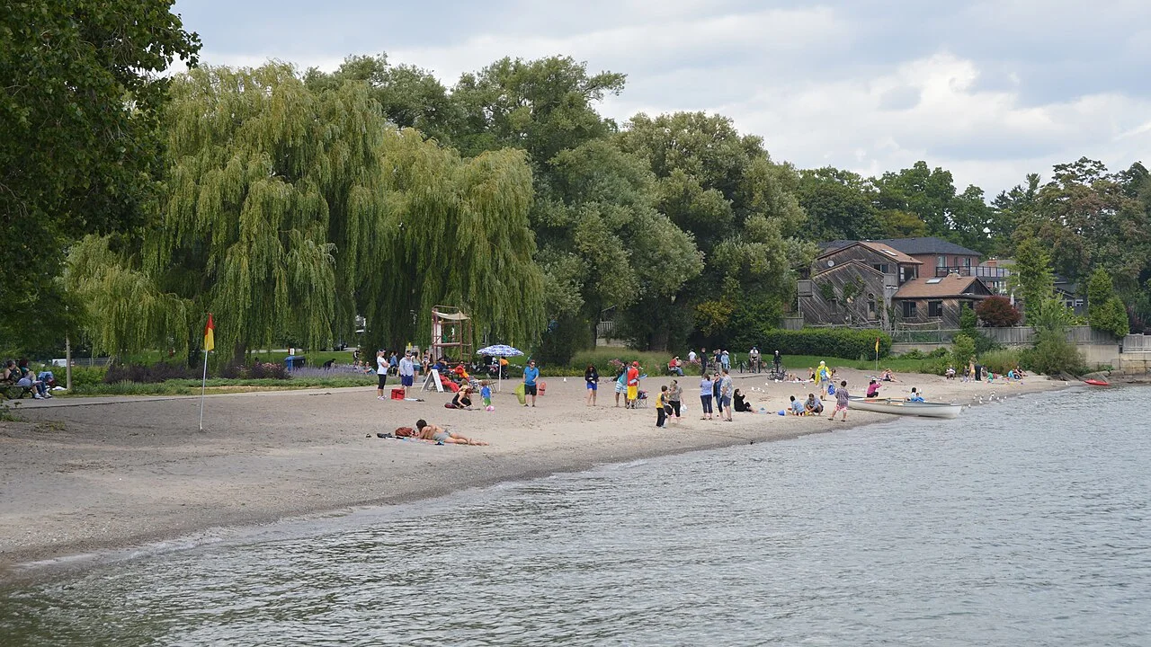 Marie Curtis Park beach with trees and people beside Lake Ontario