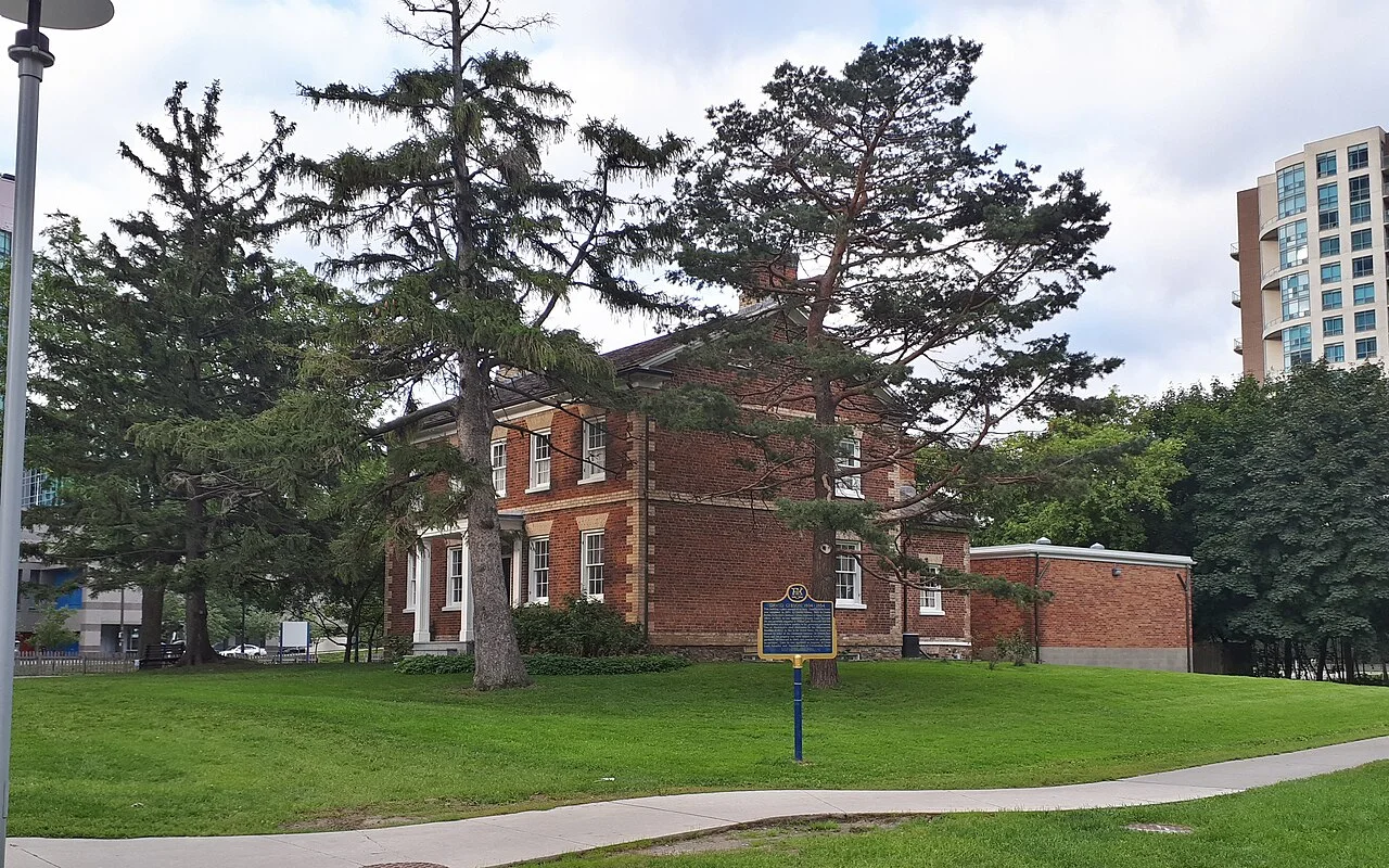 Red brick Gibson House and its lawn surrounded by North York towers
