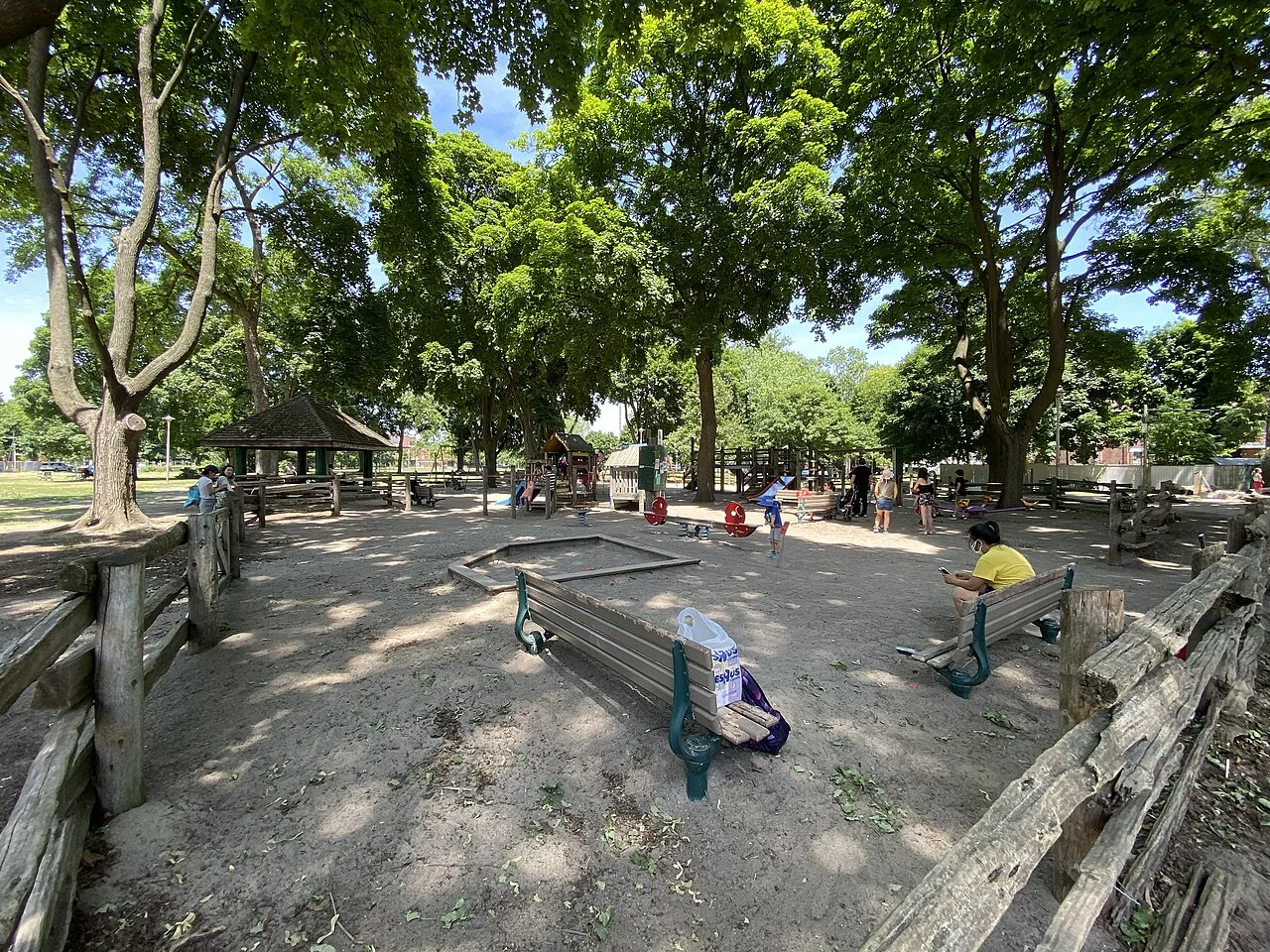 A playground and gazebo beneath trees at Dufferin Grove.