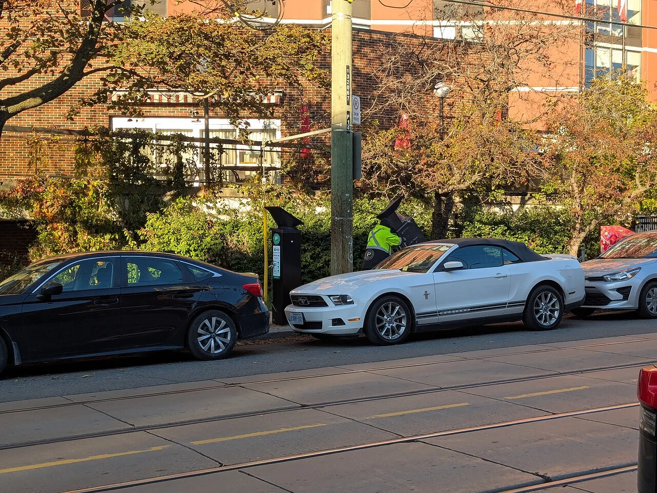 A newly installed parking pay station beside parked cars on Roncesvalles Avenue.
