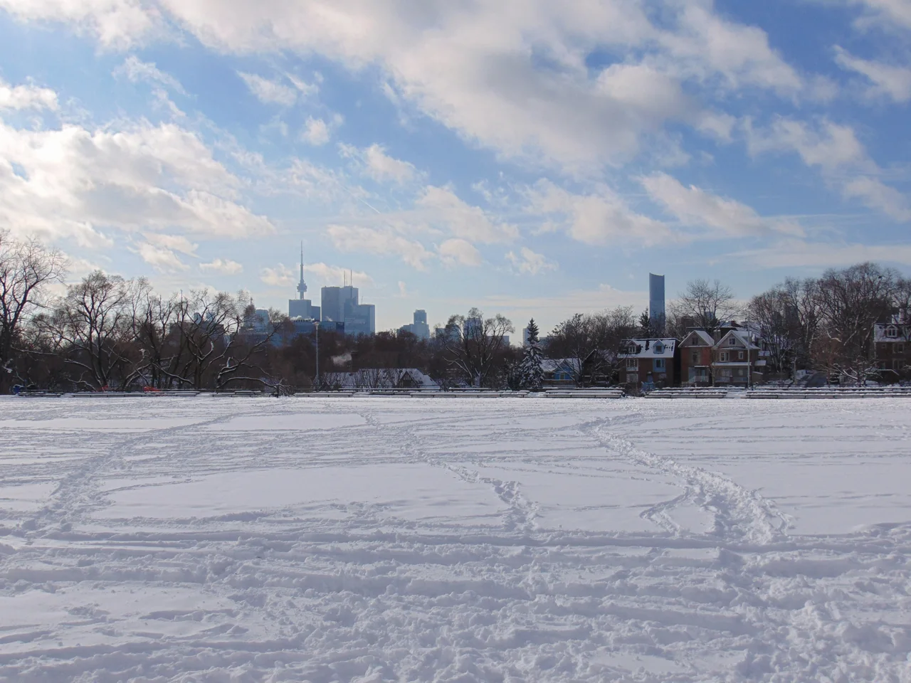 Snow-covered Withrow Park with the downtown skyline in the distance.