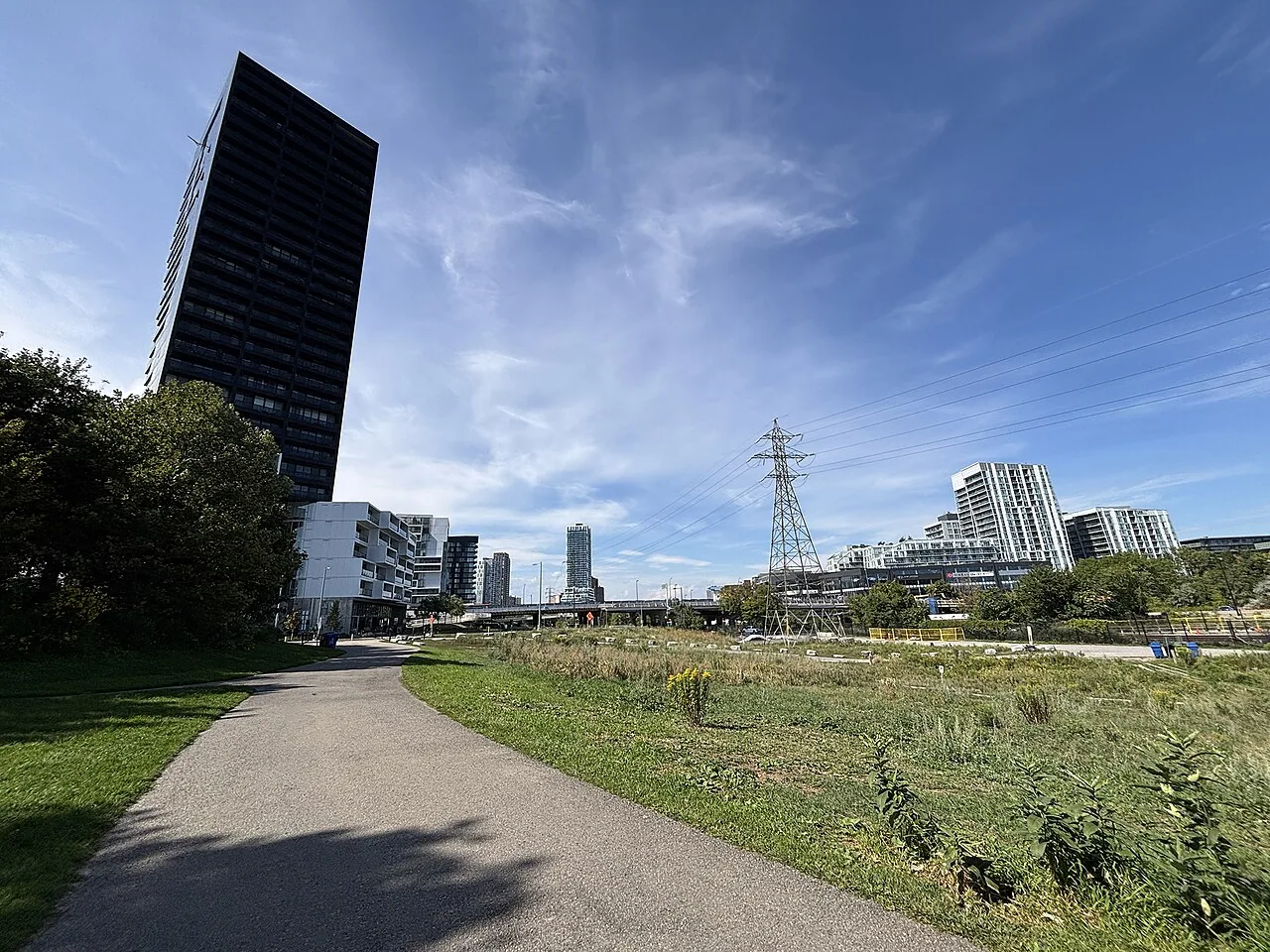 A path through Corktown Common with planting beds and residential buildings beyond.