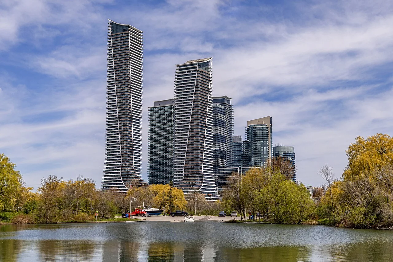 Condominium towers rising above Humber Bay Park West beside the water.