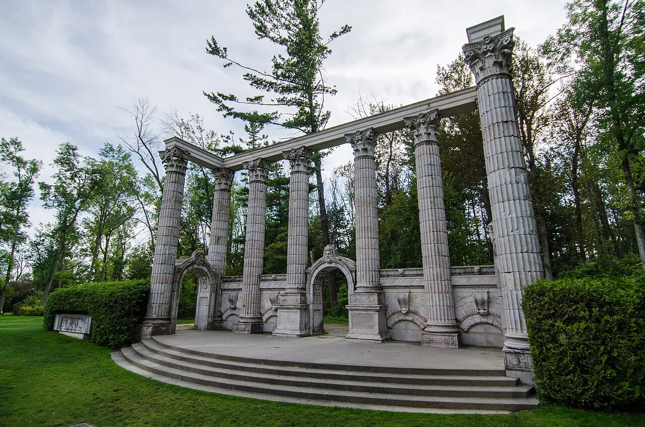 Stone columns and architectural fragments surrounded by trees in Guild Park and Gardens.