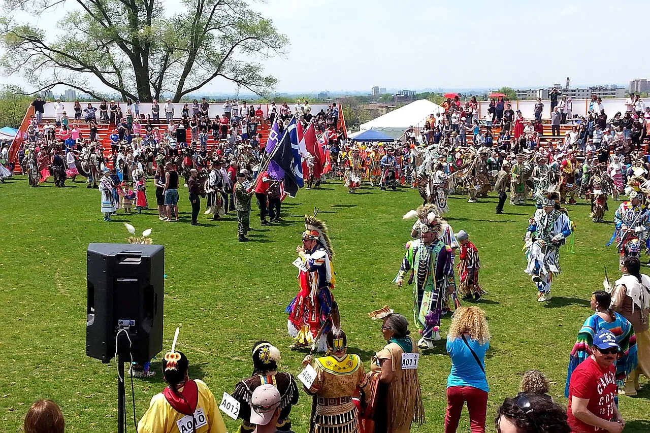 Dancers and visitors gather on a grassy field at the Native Canadian Centre of Toronto pow wow in May 2016.