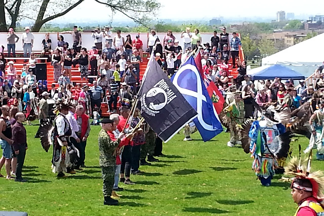 Participants carrying flags enter the gathering at the Native Canadian Centre of Toronto pow wow in 2016.